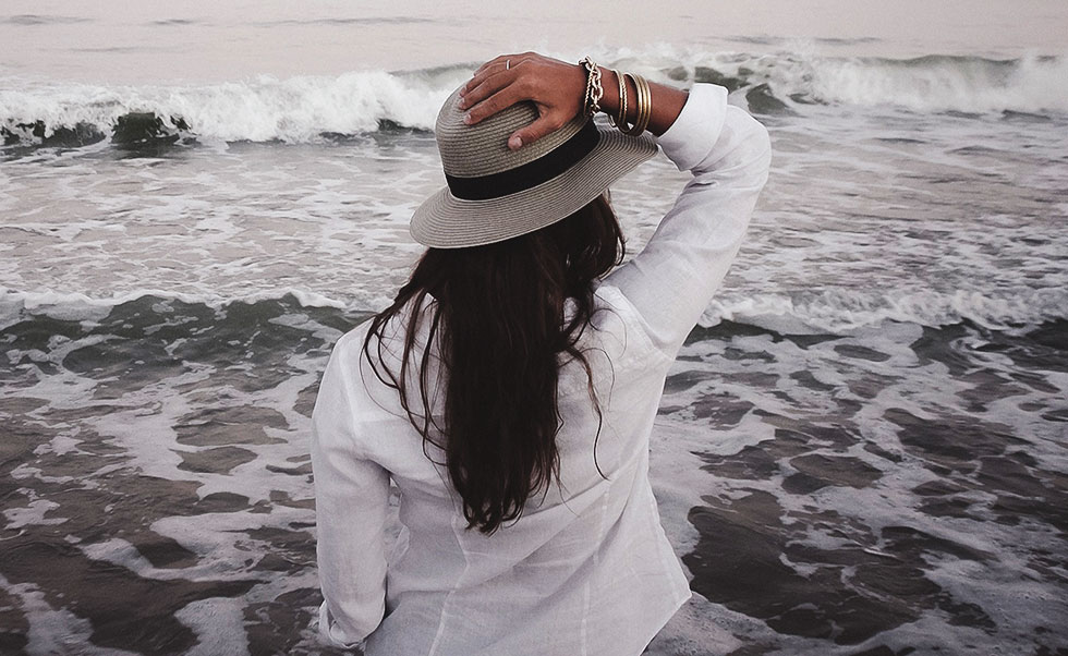 Eine Frau mit Hut am Strand.