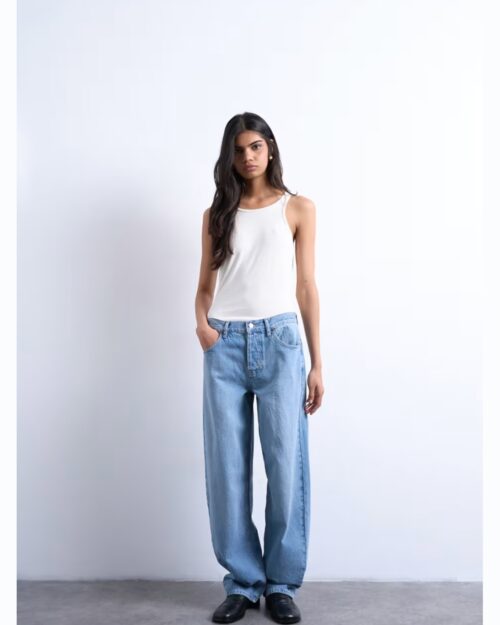 Model mit weißem Tanktop und hellblauer Baggy Jeans