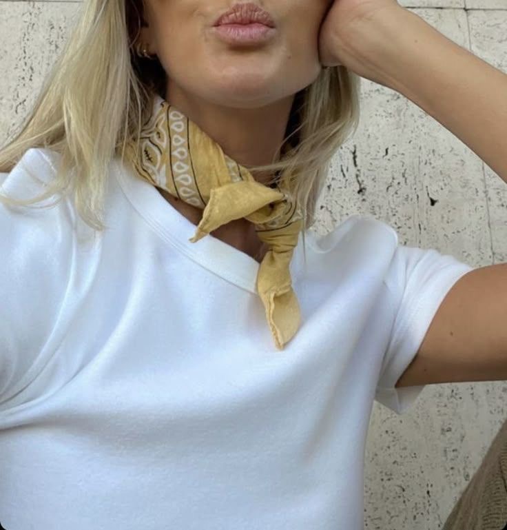 Frau stylt ein gemustertes Bandana als Halstuch zu einem weißen Shirt